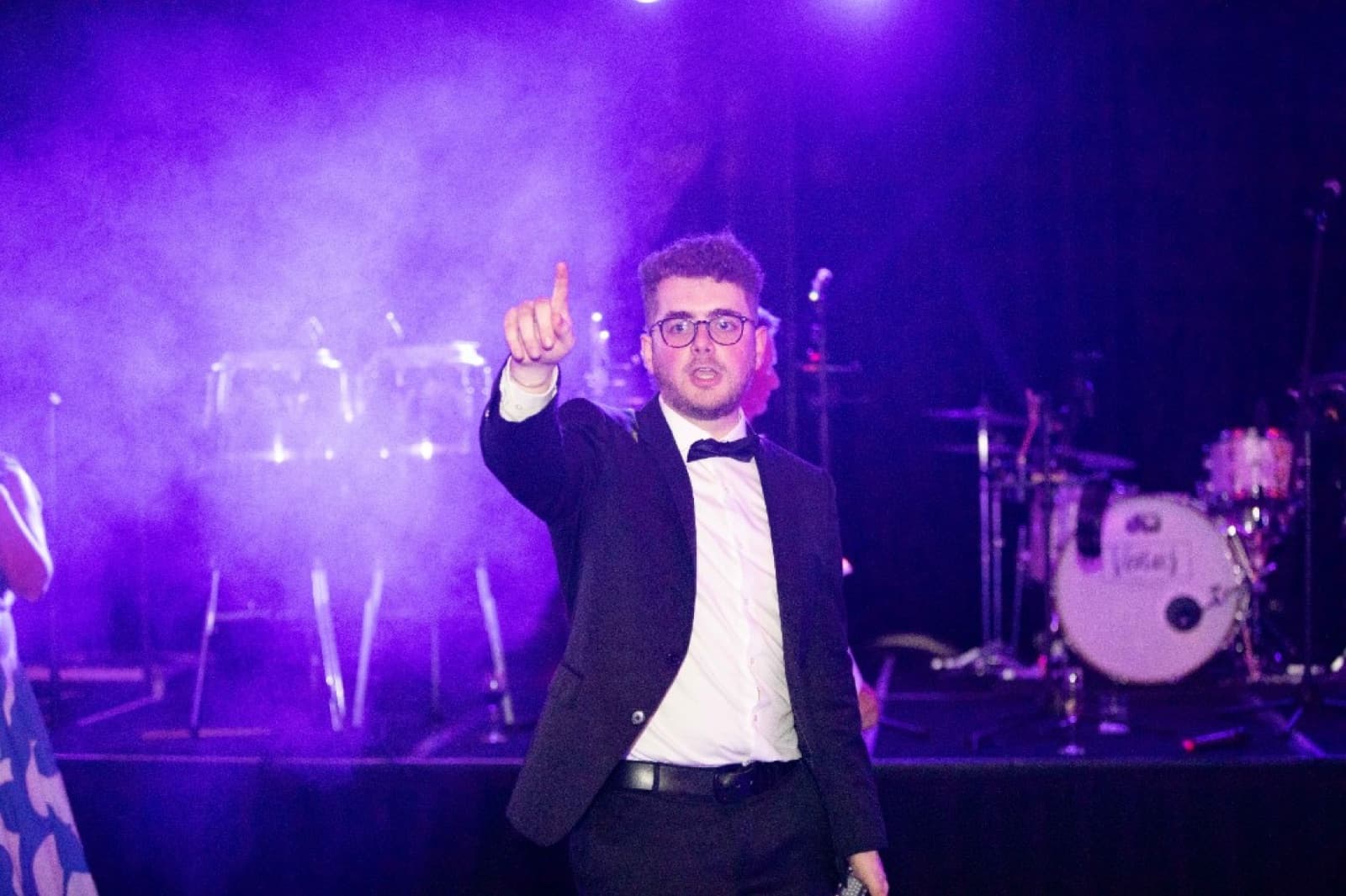 An auctioneer raising a hand mid-call during the 2025 Bloody Cells Ball live auction